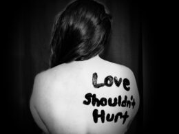 love shouldn't hurt-printed on back of woman