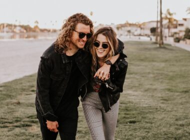 woman in black leather jacket and gray pants standing on green grass field during daytime