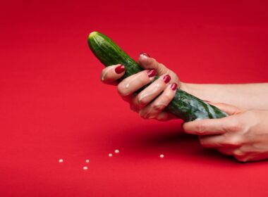 person holding green cucumber on red table