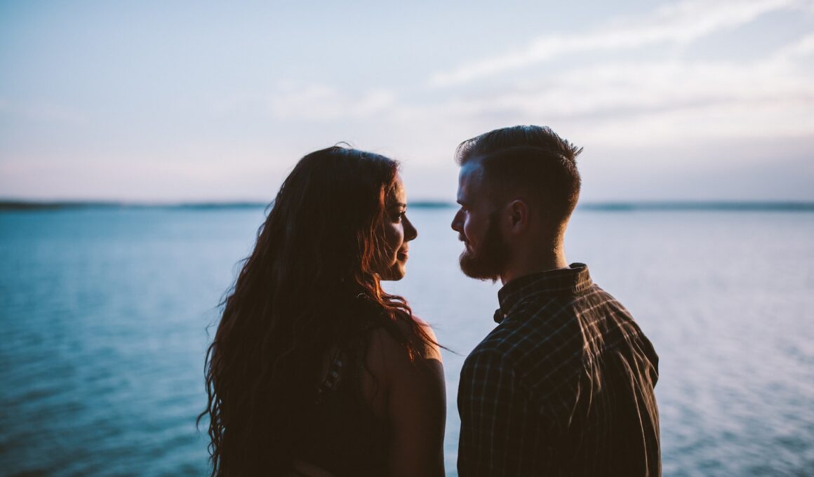 man and woman standing while looking each other near body of water