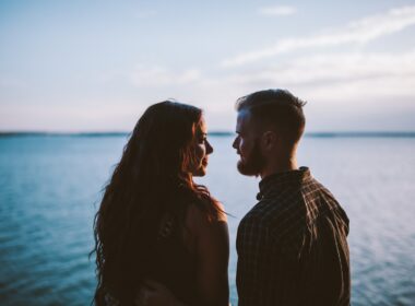 man and woman standing while looking each other near body of water