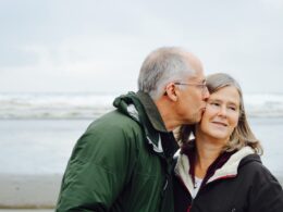 man kissing woman on check beside body of water