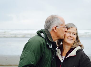 man kissing woman on check beside body of water