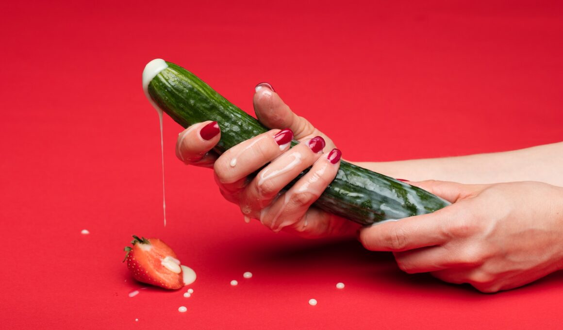 person holding green cucumber on red table