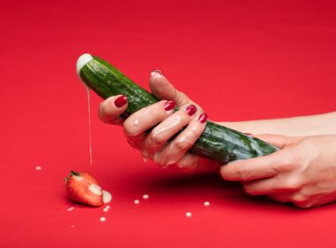 person holding green cucumber on red table