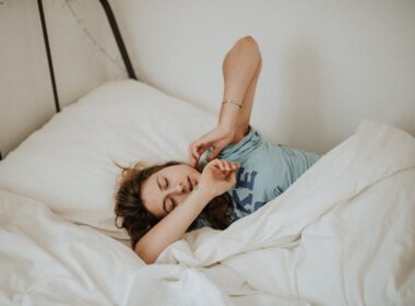 woman covered in white blanket sleeping on white bed comforter