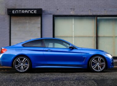 blue coupe beside gray house