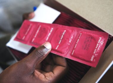 man holding red condom packs