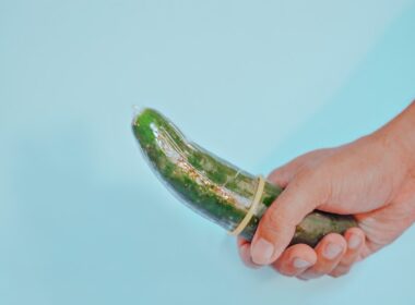 person holding green vegetable in clear glass jar